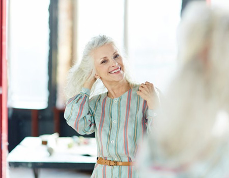 Woman smiling in the mirror and flipping her hair