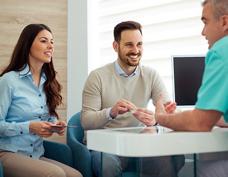 Couple discusses something with dentist