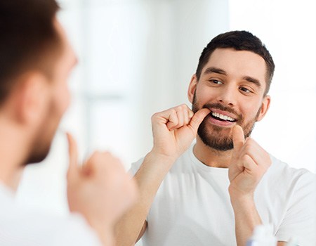 Closeup of man smiling while flossing teeth