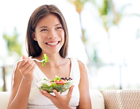 Woman smiling while eating salad outside