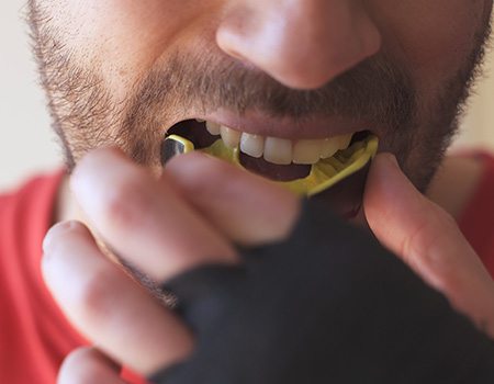 Man putting on yellow and black mouthguard